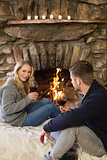 Couple with wineglasses in front of lit fireplace