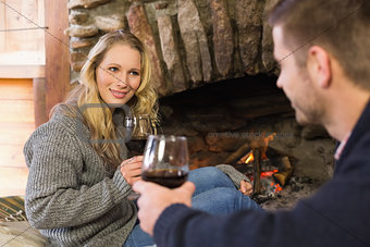 Couple with wineglasses in front of lit fireplace