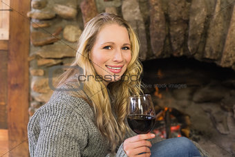 Beautiful woman with wineglass in front of lit fireplace