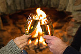 Hands toasting champagne flutes in front of fireplace