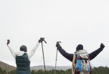 Rear view of couple raising hands after a trek