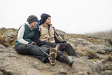Couple sitting on rock with backpack and trekking poles