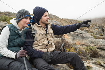 Couple on rock with trekking poles while on a hike