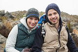 Smiling couple sitting on rock while on a hike