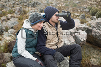 Couple sitting on rock with binoculars while on a hike