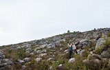 Couple standing on rocky landscape with hands raised against clear sky