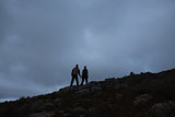 Couple on rocky landscape against the sky at night
