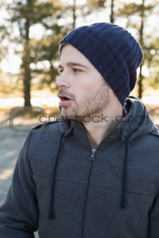 Man in warm clothing looks to his side in forest
