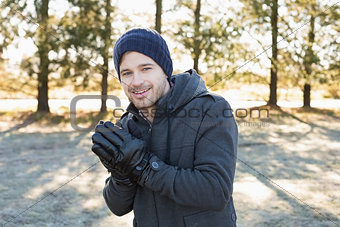 Smiling man in warm clothing shivering while having a walk in forest