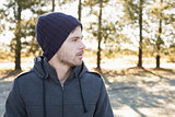Young man in warm clothing looks to his side in forest