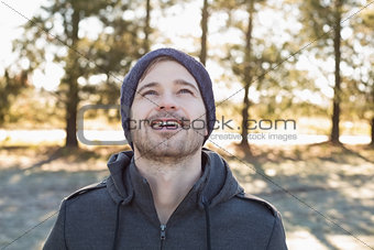 Smiling man in warm clothing looking up in forest
