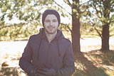 Smiling young man in warm clothing in forest