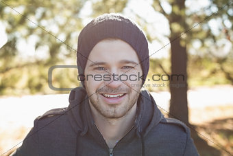 Close up of a smiling man in warm clothing in forest