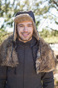 Smiling man in warm clothing standing in forest