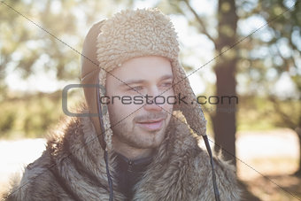 Smiling man in warm clothing looking away in forest