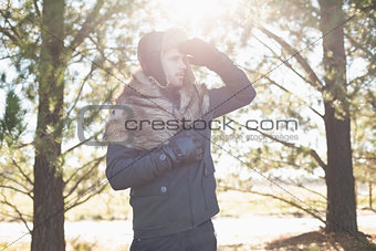 Young man in warm clothing looking away in forest