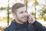 Close up of a smiling man using cellphone outdoors