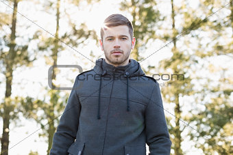 Young man in pullover standing in forest