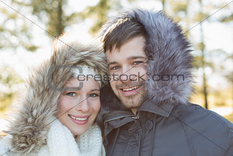 Smiling young couple in fur hood jackets in the woods