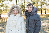 Smiling couple in fur hood jackets in the woods