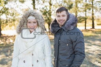 Smiling couple in fur hood jackets in the woods