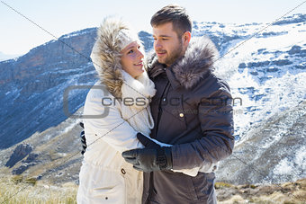 Loving couple in jackets against snowed mountain range
