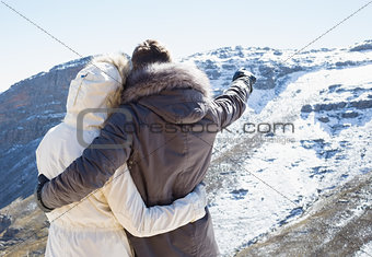 Couple in fur hood jackets looking at snowed mountain range