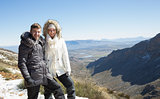 Couple in fur hood jackets against snowed mountainous valley