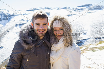 Couple in fur hood jackets against snowed mountain range