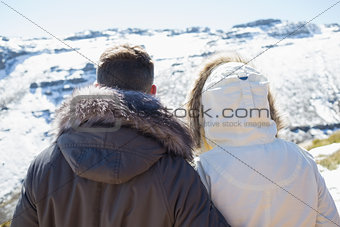 Couple in jackets looking at snowed mountain range