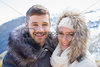 Loving couple in jackets against snowed mountain