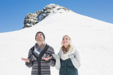 Couple with hands open looking up against snowed hill