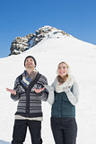 Couple with hands open looking up in front of snowed hill