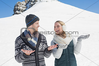Couple with hands open looking at each other in front of snowed hill