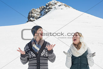 Couple with hands open standing in front of snowed hill