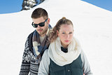 Couple in warm clothing in front of snowed hill