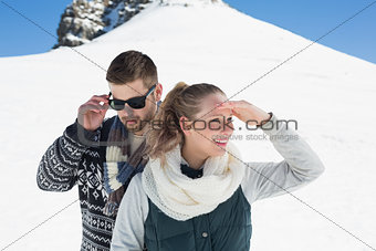 Couple in warm clothing in front of snowed hill
