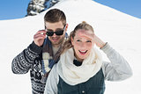 Happy couple in warm clothing in front of snowed hill