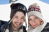 Smiling couple in woolen hats on snow covered landscape