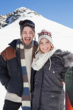 Portrait of a cheerful couple in jackets with ski board
