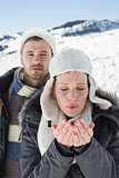 Couple with cupped hands on snow covered landscape