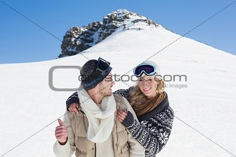 Couple in jackets and ski goggles against snowed hill