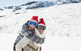 Man piggybacking cheerful woman on snow