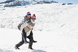 Full length of a man piggybacking cheerful woman on snow