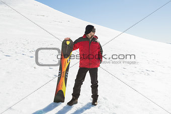Full length of a man with ski board looking away on snow
