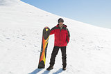 Smiling man with ski board standing on snow