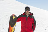 Portrait of a serious man with ski board standing on snow