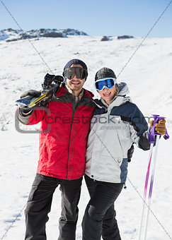 Portrait of a cheerful couple with ski boards on snow
