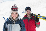 Portrait of a smiling couple with ski boards on snow