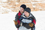 Happy man embracing woman from behind on snow
